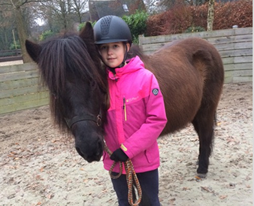 Ein kleines Mädchen mit einer rosa Jacke und einem Islandpferd